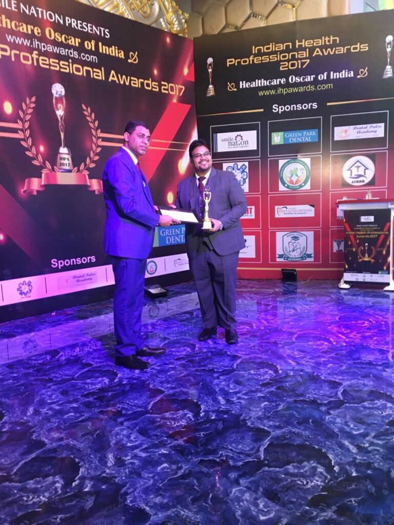Dr. Mohit Gupta receiving a dental award on stage